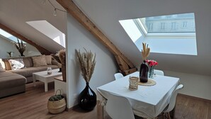 A cozy loft-style living space with a dining area, a sofa set, and a skylight. - Charming cocoon in the heart of the spa district (Vittel)