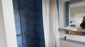 Een badkamer met een douche, een dweil, een spiegel en een wastafel.