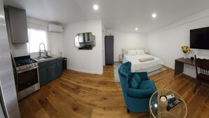 A modern hotel room with a kitchen, a bed, a TV, and a seating area. - Updated Studio in LA with refreshing AC & Washer/Dryer (Los Angeles)