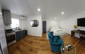 A modern hotel room with a kitchen, a bed, a TV, and a seating area. - Updated Studio in LA with refreshing AC & Washer/Dryer (Los Angeles)