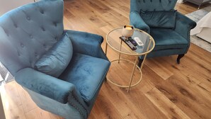 A room with two blue armchairs, a small round table with a candle, and a remote control. - Updated Studio in LA with refreshing AC & Washer/Dryer (Los Angeles)