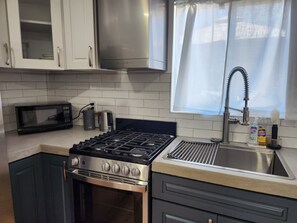 Una cocina moderna con estufa a gas, horno, microondas y electrodomésticos de acero inoxidable.