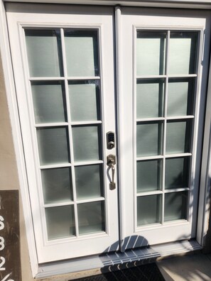 A white double door with a frosted glass pattern, a metal handle, and a small step leading up to it. - Updated Studio in LA with refreshing AC & Washer/Dryer (Los Angeles)