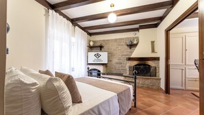 A bedroom with a bed, a stone fireplace, and a kitchen area visible through an open door. - La Perla del Sangro (Castel di Sangro)
