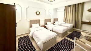 A hotel room with two beds, a wooden door, a chandelier, and a mirror on the wall. - Spacious 4-bedroom apartment in awesome Giza Governorate with AC (Giza Governorate)