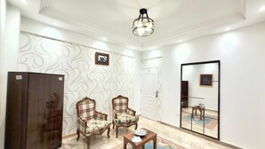 A room with a large wardrobe, two plaid chairs, a small table, a mirror, and a patterned rug. - Spacious 4-bedroom apartment in awesome Giza Governorate with AC (Giza Governorate)