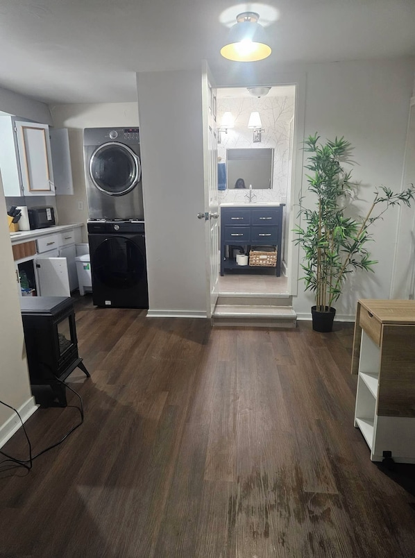Un espacio habitable compacto con cocina, lavadora, un pequeño comedor y un baño con espejo y lavamanos.