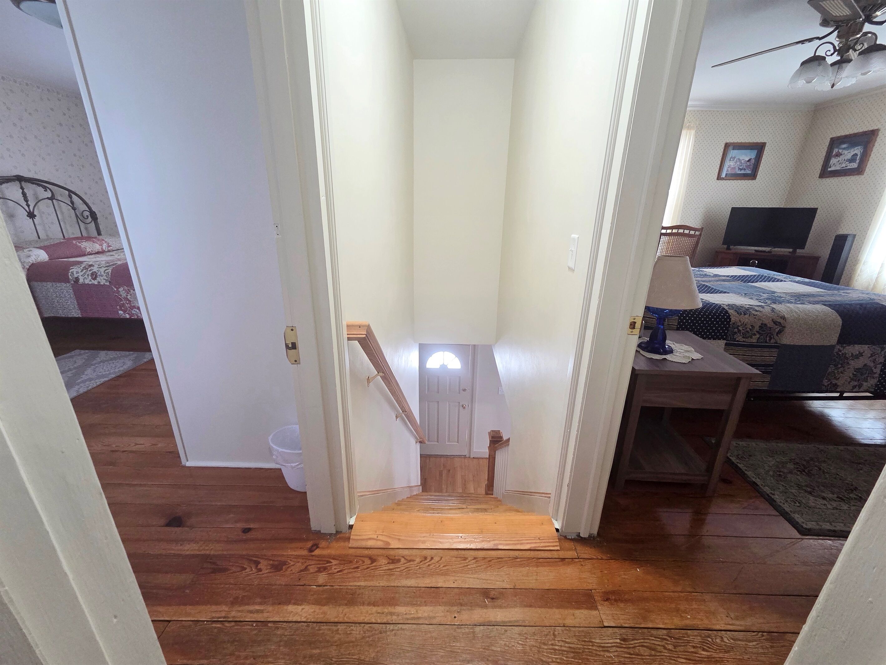 Eine enge Treppe führt zu einem Schlafzimmer mit Bett, Schreibtisch und Fernseher.