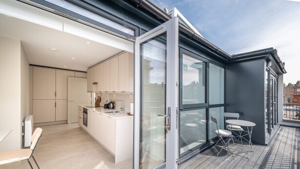 A modern kitchen with white cabinets, a central island, and a dining area with a table and chairs.