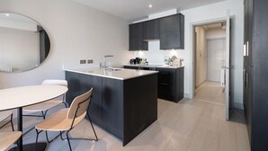 Una cocina moderna con una isla central, armarios oscuros y un comedor con una mesa redonda y sillas.