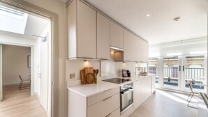 Una cocina moderna con armarios blancos, horno empotrado y un amplio ventanal con vistas a un balcón.
