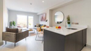 Una cocina moderna con una isla central, un área de comedor con sofá y sillas, y un ventanal que proporciona luz natural.
