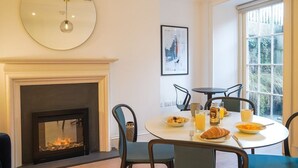 Een eethoek met een open haard, een ronde spiegel en een gedekte tafel voor het ontbijt.