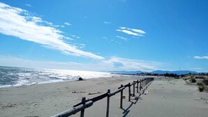 Een strand met een houten omheining, een zandstrand en een heldere lucht.