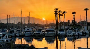 A marina with boats docked, palm trees, and a mountain in the background. - L'Ecrin de la plage, 3-star house, 100m from the beach (Sainte-Marie-la-Mer)
