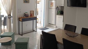 Een moderne keuken met een televisie, een eethoek met stoelen en uitzicht buiten.