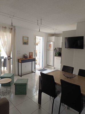 A modern kitchen with a TV, dining area with chairs, and a view to the outside. - L'Ecrin de la plage, 3-star house, 100m from the beach (Sainte-Marie-la-Mer)
