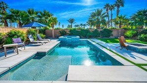 A swimming pool with lounge chairs and a palm tree-lined garden. - Platinum Luxury @ PGA West (La Quinta)