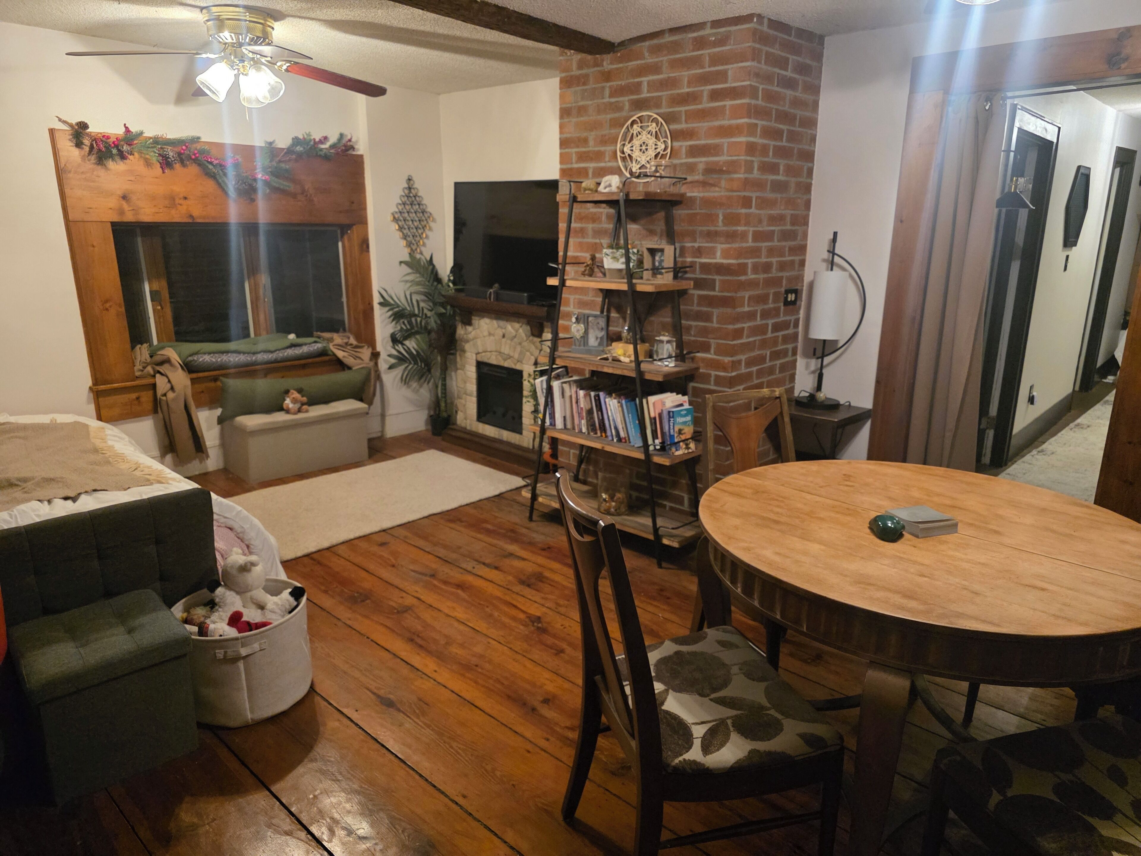 Una sala de estar acogedora con chimenea, una estantería, una mesa redonda de madera y un sofá.