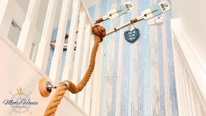 A staircase with a rope handrail, striped wall, and a sign that says "TAKE ME TO THE BEACH." - Superb Moorehouse Holiday Let private garden games room  & bar Pet freindly! (Thornton-Cleveleys)
