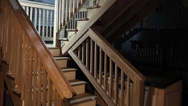 Eine Holztreppe mit Geländer, die zu einer oberen Ebene führt.