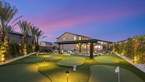 Un campo da golf con un club house, erba ben curata e un cielo al tramonto.