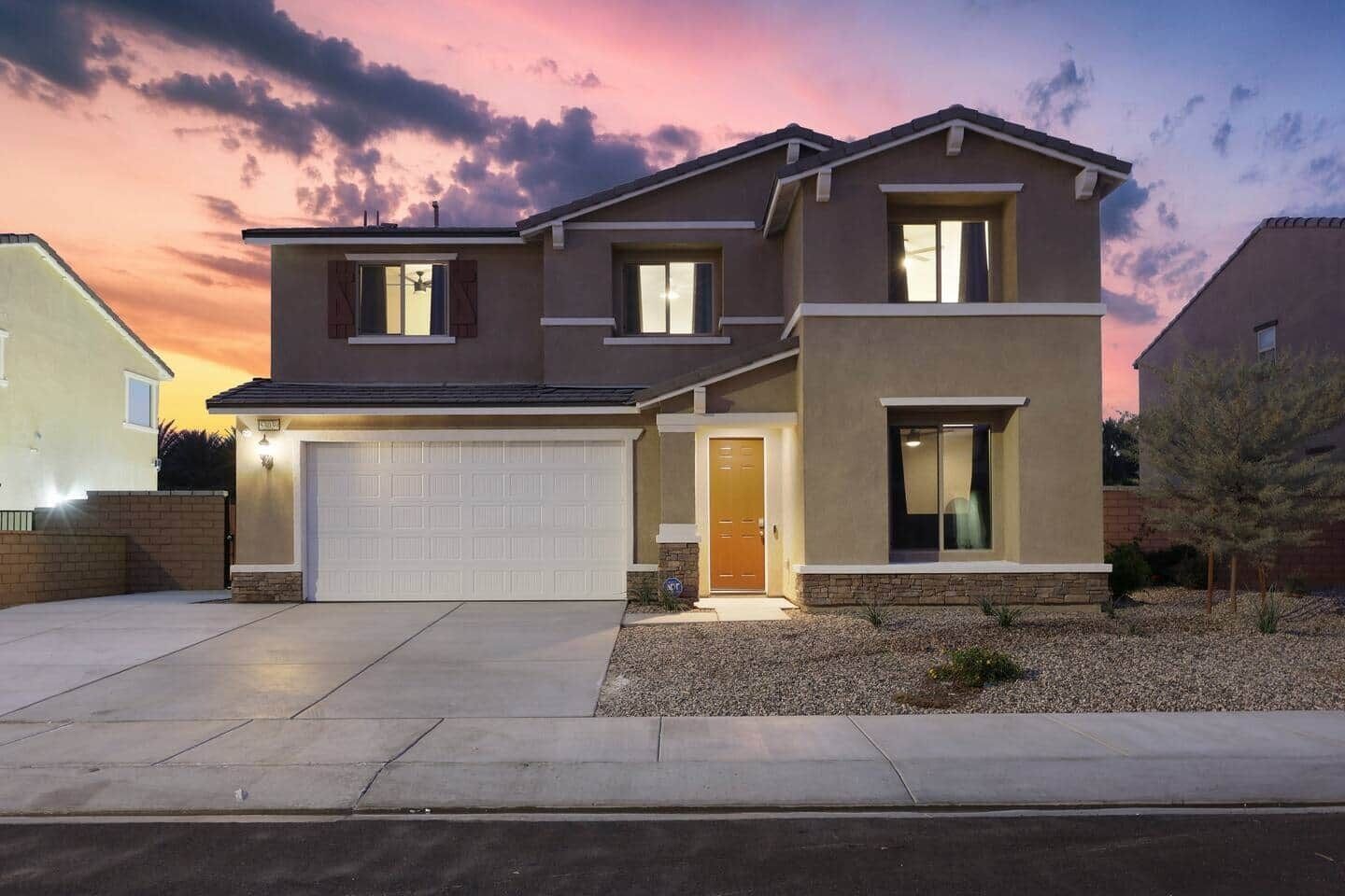 Ein zweistöckiges Haus mit Garage, Eingangstür und kleinem Vorgarten.