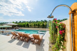 Ein Poolbereich mit Liegestühlen, einer Rutsche und einer Wandbrause.