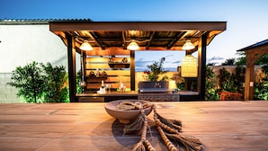 Un área de cocina exterior con una mesa de madera, un cuenco y un cartel que indica las normas de la cocina exterior.