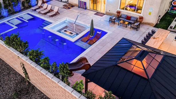 Una piscina con sillas de descanso, un jacuzzi y una zona de estar cubierta.