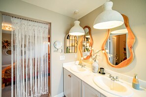 Ein Badezimmer mit zwei Waschbecken, einem großen Spiegel und Pendelleuchten.