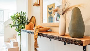 Un interior de hogar con una encimera de cocina, una planta en maceta, un cuenco de fruta y un jarrón decorativo.