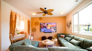 Una sala de estar moderna con un conjunto de sofá, un televisor montado en la pared y un ventilador de techo.