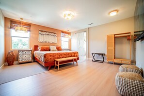 Ein geräumiges Schlafzimmer mit einem großen Bett, einer Holzbank, einem Kleiderschrank und einem Spiegel.