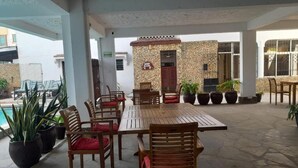 An outdoor patio with a wooden table and chairs, surrounded by potted plants and a stone wall. - Global African Apart-Hotel Mtwapa (Mtwapa)