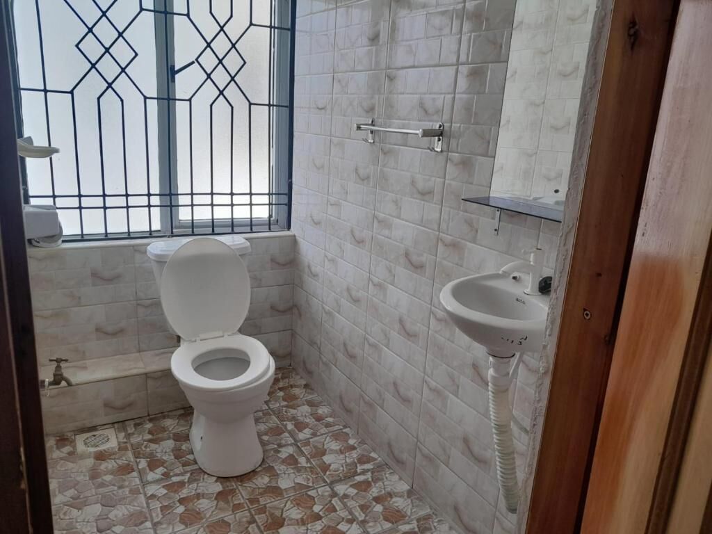 Um banheiro pequeno com vaso sanitário, pia e janela com grades de metal.