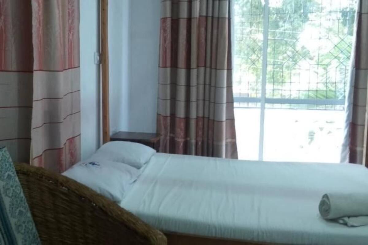 A room with a bed, a chair, and a window with curtains.