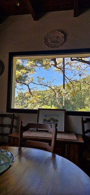 A dining area with a large window, wooden chairs, and a table. - Beautiful family home with sea view (Carqueiranne)