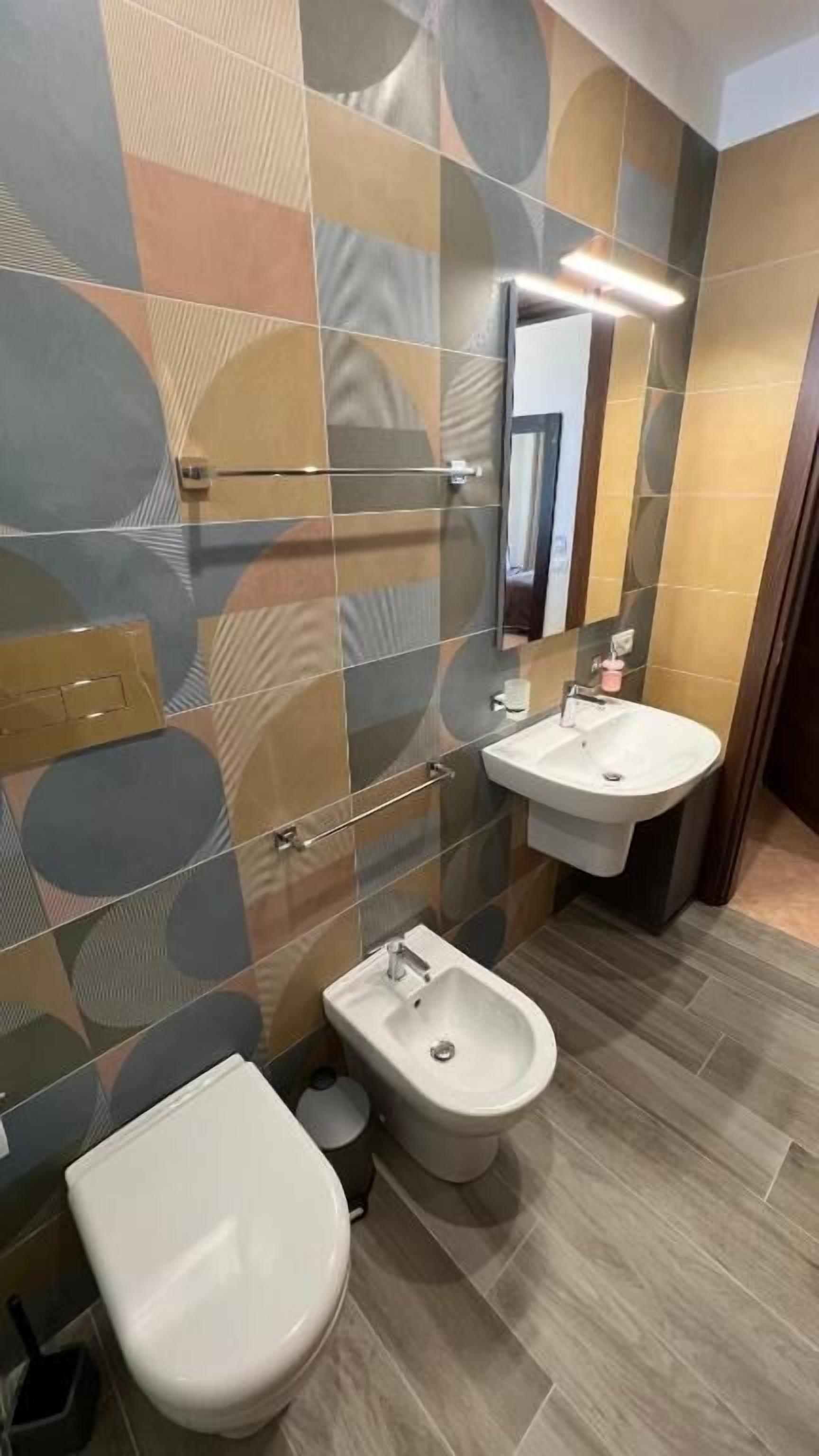 A modern bathroom with a toilet, bidet, and two sinks.