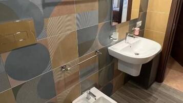A modern bathroom with a toilet, bidet, and two sinks.