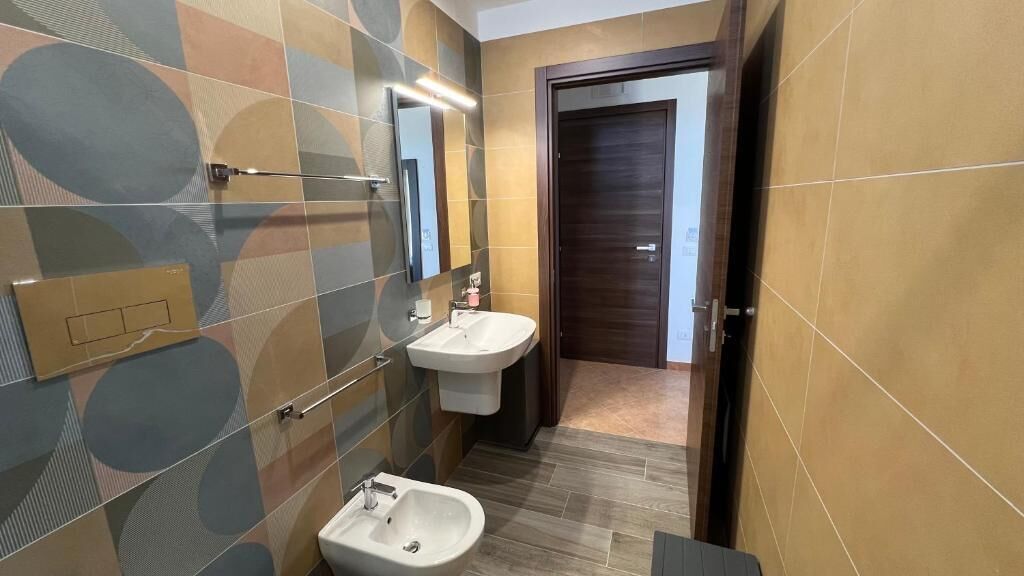 Casa de banho moderna com um espelho grande, duas pias e um bidé.