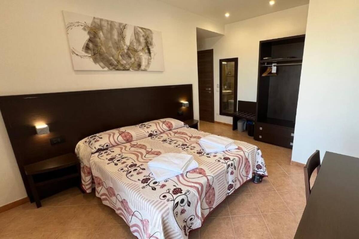 A bedroom with a large bed, a bedside table, a dresser, a mirror, and a small table with a chair.