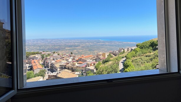 Blick aus einem Fenster auf eine Stadt mit Gebäuden und blauem Himmel.