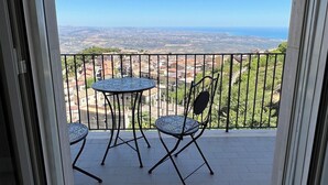 Ein Balkon mit Tisch und Stühlen, der einen Blick auf eine entfernte Landschaft bietet.