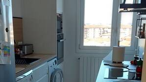 Eine kompakte Küche mit Waschmaschine, Backofen und Fenster mit Blick.