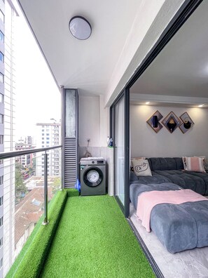 A modern apartment with a balcony, a washing machine, a bed, and a city view. - Apartment in Nairobi, Kilimani (nairobi)