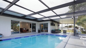 A swimming pool with a glass ceiling, a covered patio area, and a view of the outdoors. - Waterfront Canal Home with Private Pool . Family Getaway . New Rental (Cape Coral)