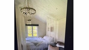 Une pièce avec un lit, un lustre et une fenêtre.