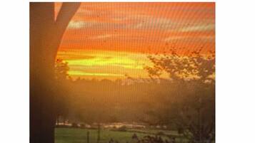 A sunset view through a window with a fence in the foreground.