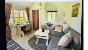 Un salon confortable avec un canapé, une petite table, un bureau et une fenêtre avec des rideaux.